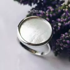 Креативное кольцо Whitelake из серебра с белым перламутром, лежащее на белом фоне рядом с сиренью