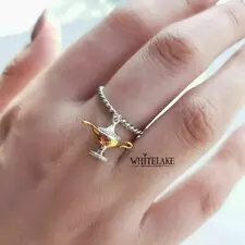Стильное кольцо в виде лампы Джинна из Аладдина из серебра с вставками фианитов и позолотой, надетое на средний палец женской руки.