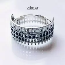 Уникальное кольцо в виде Колизея из серебра, лежащее на белом фоне.